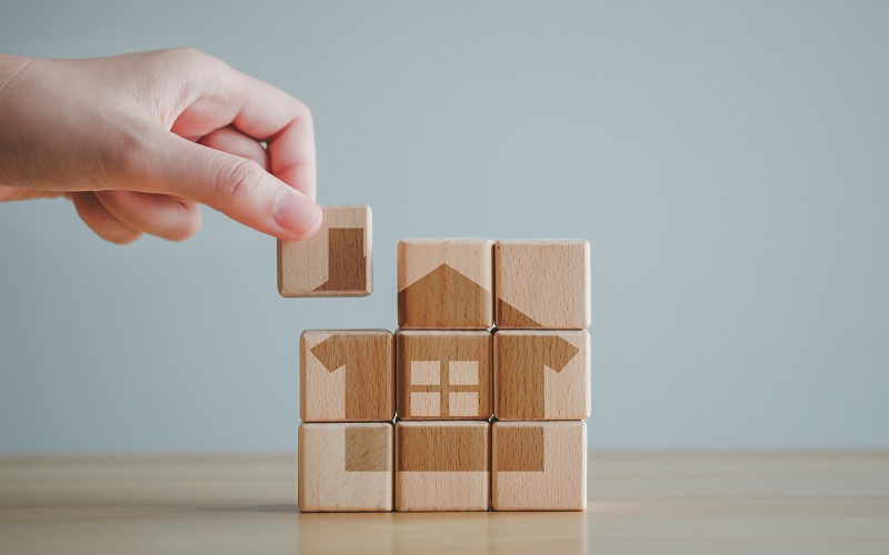 and asset management, Housing finance and home loan concept. Hand puting part of house into wooden blocks refer to start a family or buy or rent home.